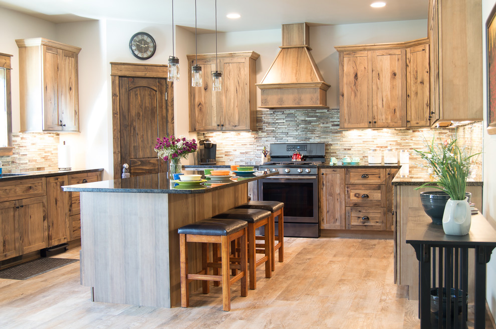 Mountain style u-shaped beige floor eat-in kitchen photo with shaker cabinets, brown cabinets, granite countertops, brown backsplash, stainless steel appliances, an island and gray countertops