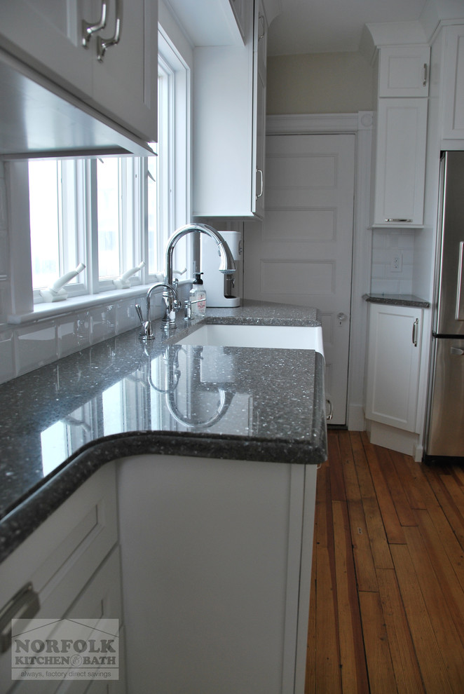Inspiration for a small transitional u-shaped light wood floor eat-in kitchen remodel in Boston with a farmhouse sink, recessed-panel cabinets, white cabinets, quartz countertops, white backsplash, subway tile backsplash, stainless steel appliances and a peninsula