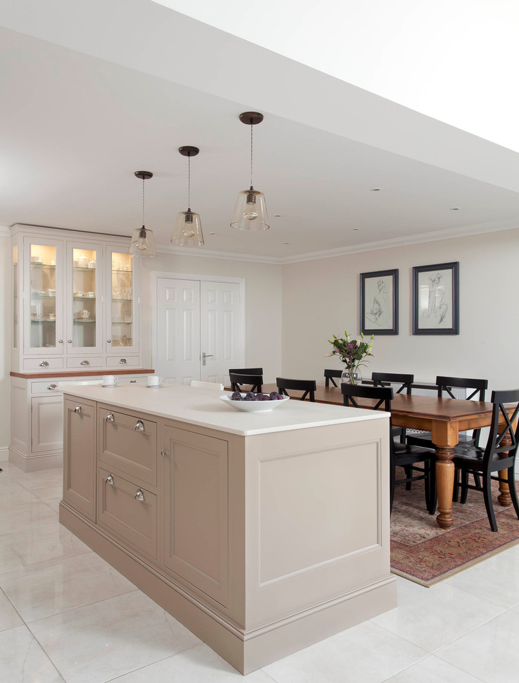 This is an example of a large transitional single-wall open plan kitchen in Dublin with an undermount sink, beaded inset cabinets, beige cabinets, quartzite benchtops, beige splashback, stone slab splashback, stainless steel appliances, porcelain floors and with island.