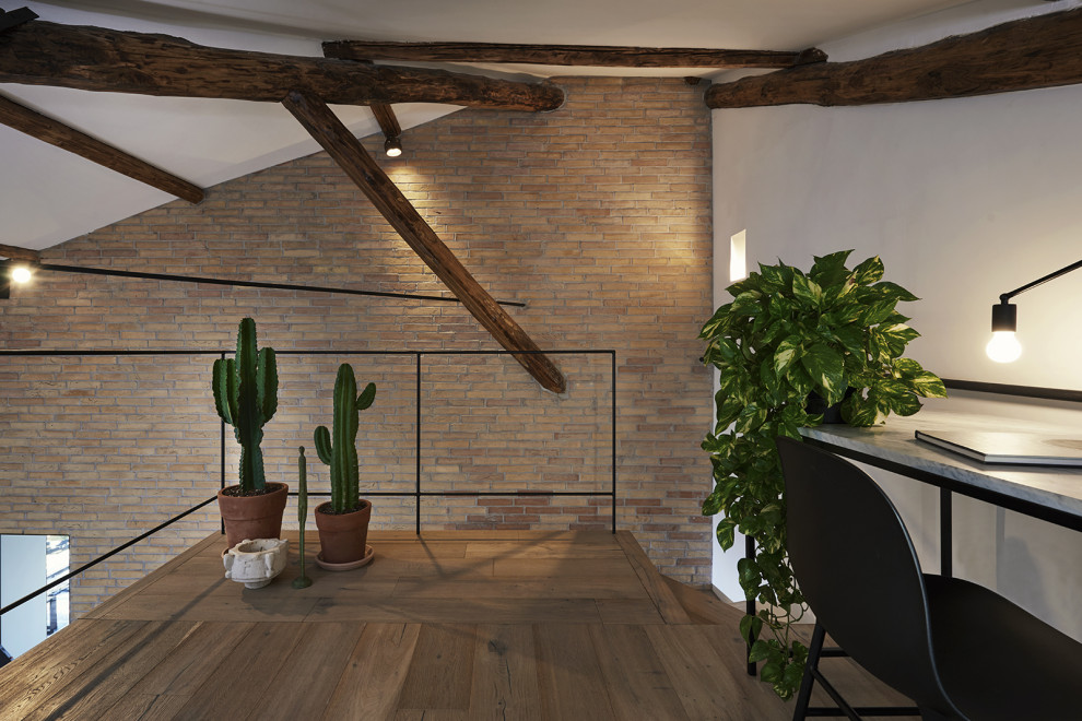 Modernes Arbeitszimmer mit Studio, hellem Holzboden, freigelegten Dachbalken und Ziegelwänden in Rom