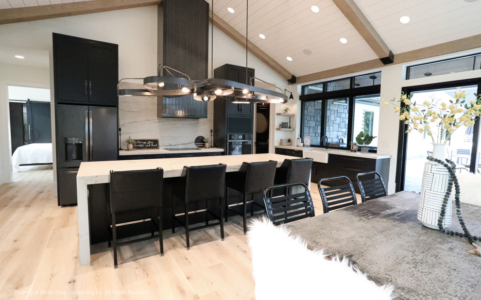 Photo of a large urban galley kitchen/diner in Other with a belfast sink, shaker cabinets, black cabinets, quartz worktops, white splashback, stone slab splashback, black appliances, light hardwood flooring, an island, white worktops and a timber clad ceiling.