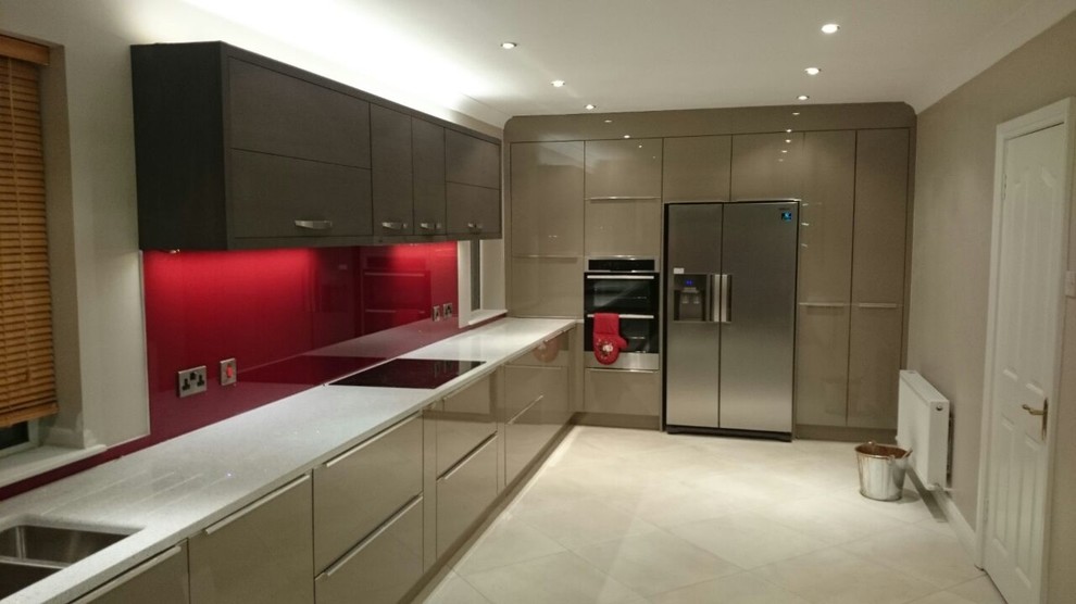 This is an example of a large contemporary u-shaped eat-in kitchen in Dublin with an undermount sink, beige cabinets, recycled glass benchtops, red splashback, glass tile splashback, white appliances, ceramic floors and no island.