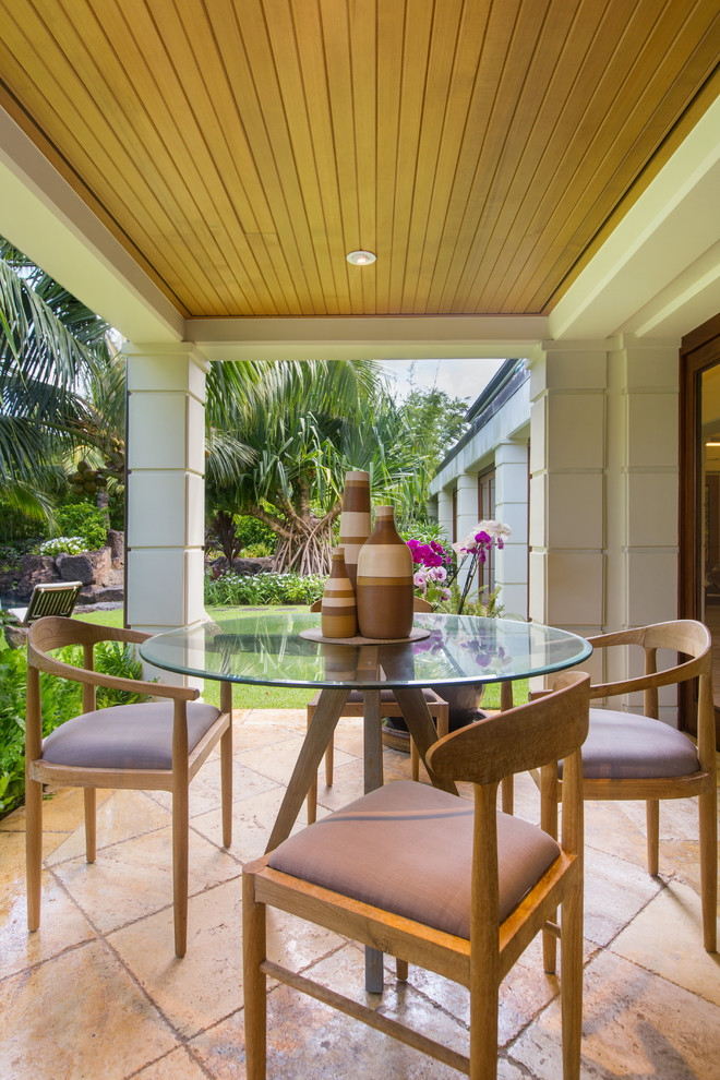 This is an example of a small tropical backyard patio in Hawaii with tile and a roof extension.