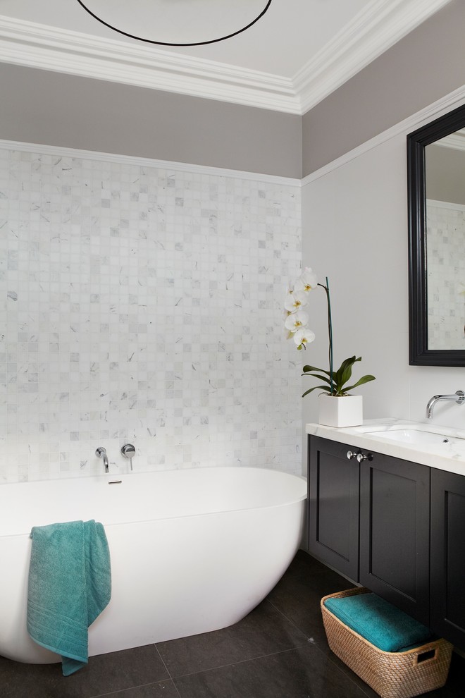 Design ideas for a transitional bathroom in Sydney with beaded inset cabinets, dark wood cabinets, a freestanding tub, white tile, mosaic tile, grey walls, travertine floors, an integrated sink, marble benchtops and black floor.