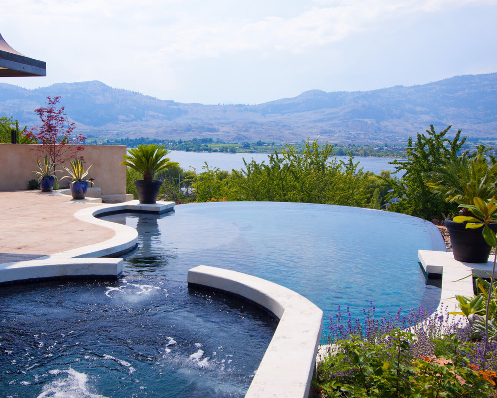 This is an example of a contemporary backyard custom-shaped infinity pool in Vancouver with a hot tub.