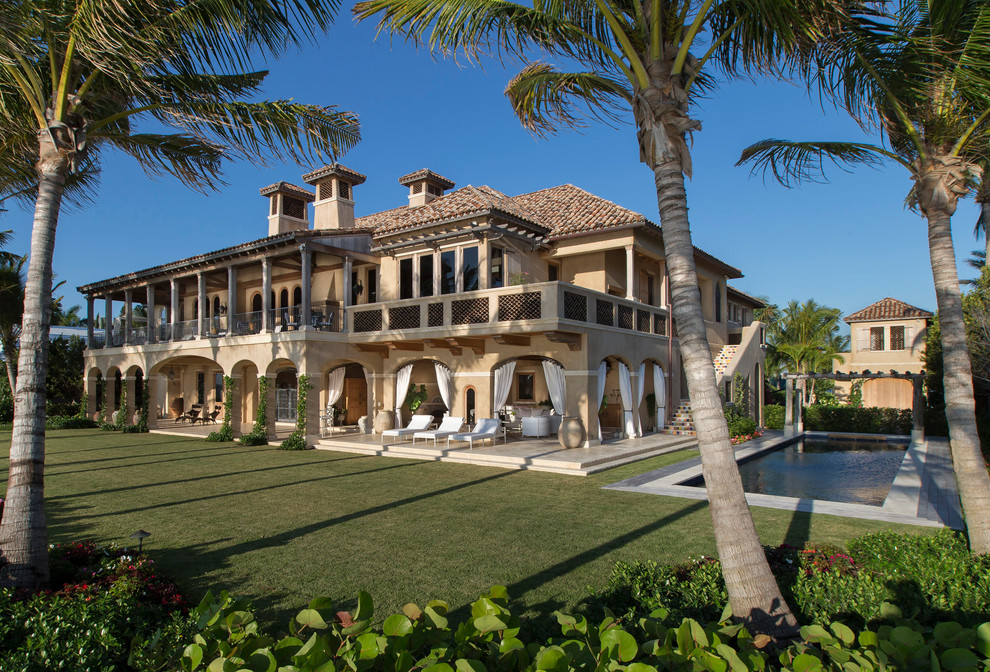 This is an example of a mediterranean two-storey brown house exterior in Miami with a hip roof and a tile roof.