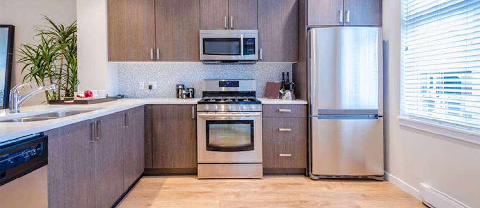 Inspiration for a mid-sized l-shaped light wood floor kitchen remodel with a double-bowl sink, flat-panel cabinets, medium tone wood cabinets, gray backsplash, stainless steel appliances and no island