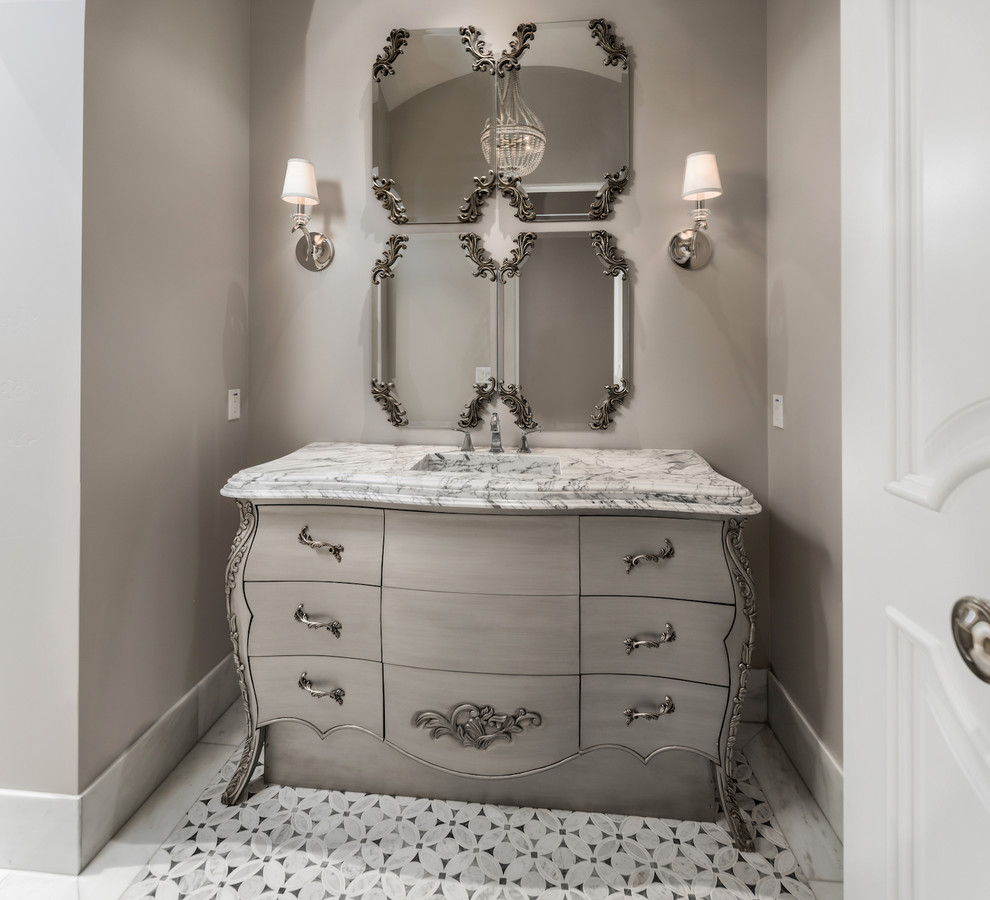 Photo of an expansive transitional master bathroom in Phoenix with furniture-like cabinets, grey cabinets, a claw-foot tub, a double shower, a one-piece toilet, beige tile, mirror tile, beige walls, mosaic tile floors, a drop-in sink, marble benchtops, beige floor and a hinged shower door.