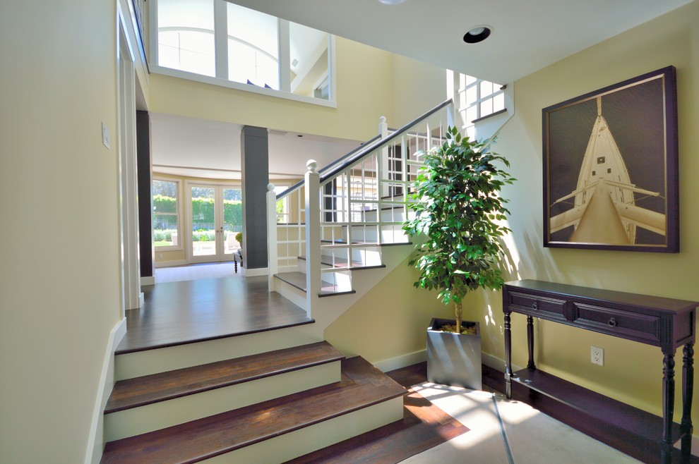 This is an example of a large traditional foyer in San Diego with dark hardwood floors and yellow walls.