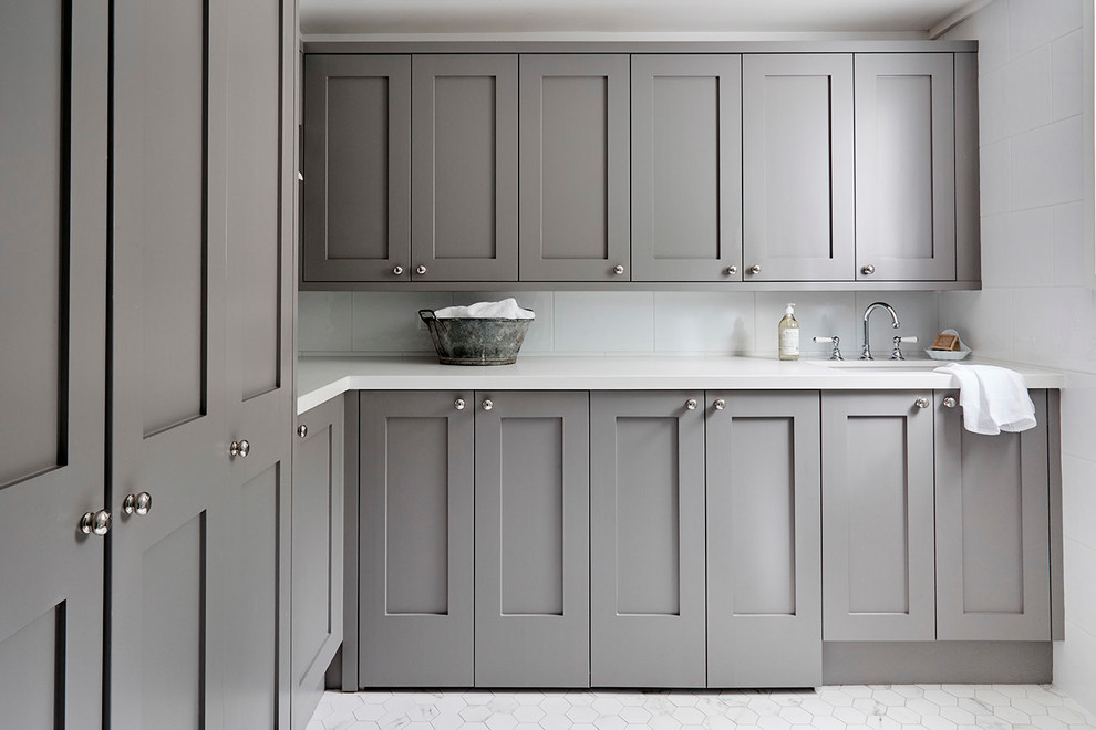 This is an example of a transitional l-shaped dedicated laundry room in Sydney with an undermount sink, shaker cabinets, grey cabinets, white walls, marble floors and white floor.