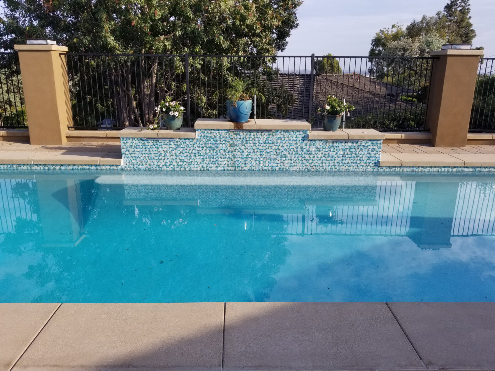 This is an example of a mid-sized beach style backyard custom-shaped natural pool in Orange County with with privacy feature and brick pavers.