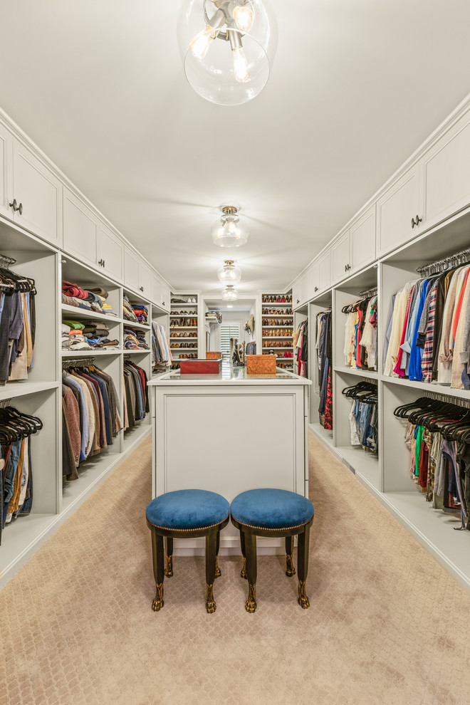 Large traditional gender-neutral walk-in wardrobe in Cleveland with recessed-panel cabinets, white cabinets, carpet and beige floor.