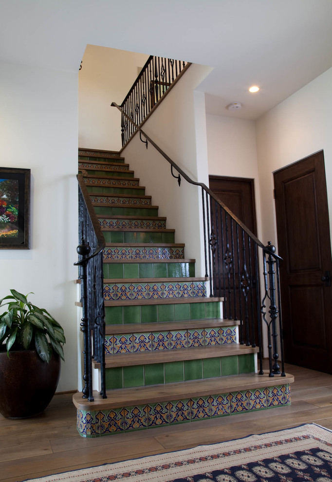 This is an example of a mid-sized mediterranean wood straight staircase in San Diego with tile risers.
