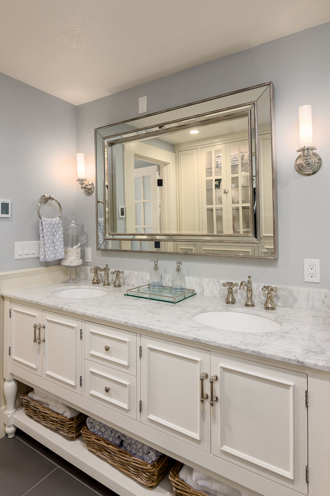 Photo of an expansive country master bathroom in Portland with raised-panel cabinets, white cabinets, a corner shower, a two-piece toilet, white tile, porcelain tile, grey walls, porcelain floors, an undermount sink, marble benchtops, grey floor, a hinged shower door, white benchtops, a double vanity and a freestanding vanity.