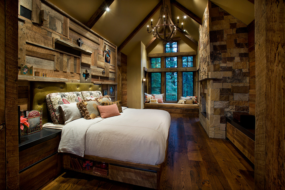 This is an example of a large country guest bedroom in Sacramento with dark hardwood floors, a standard fireplace, a stone fireplace surround, beige walls and brown floor.