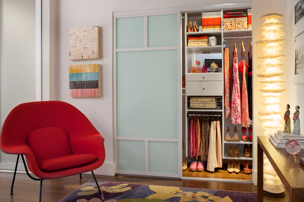 Small modern gender-neutral built-in wardrobe in New York with flat-panel cabinets, white cabinets and medium hardwood floors.