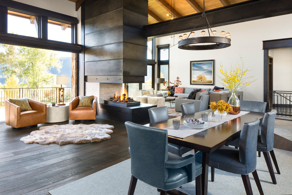 Inspiration for a large contemporary open plan dining in Denver with white walls, dark hardwood floors, a two-sided fireplace and a metal fireplace surround.