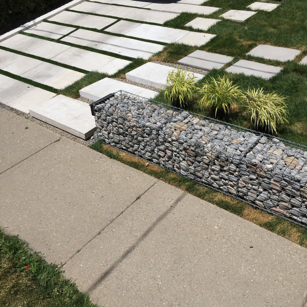 Design ideas for a mid-sized modern front yard partial sun driveway in Toronto with a retaining wall and concrete pavers.