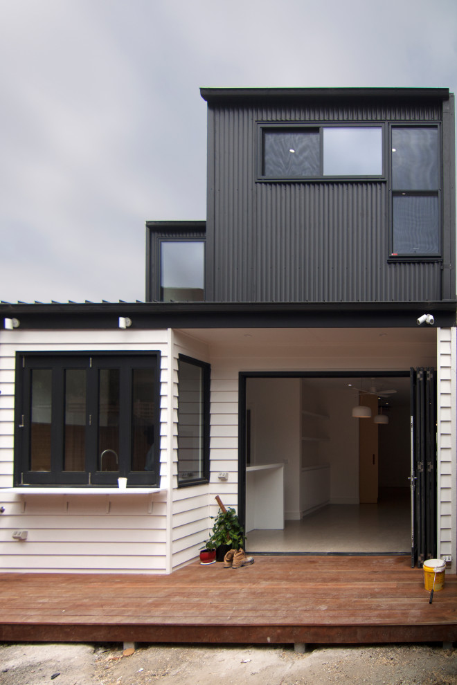 Inspiration for a small contemporary two-storey black townhouse exterior in Melbourne with mixed siding, a gable roof, a metal roof and a black roof.