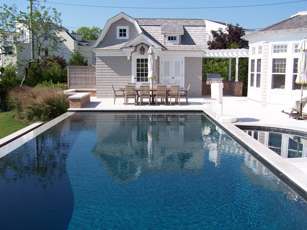 Transitional backyard custom-shaped pool in New York with a water feature and natural stone pavers.
