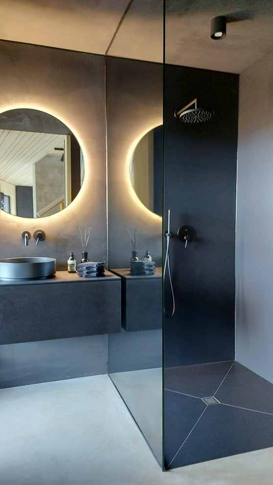 This is an example of an expansive contemporary 3/4 bathroom in Frankfurt with flat-panel cabinets, black cabinets, a curbless shower, a two-piece toilet, grey walls, a vessel sink, grey floor, an open shower, black benchtops, a single vanity and a floating vanity.