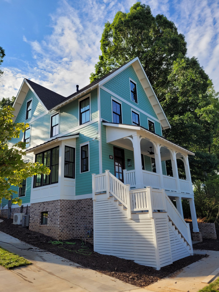 Example of a mid-sized beach style green three-story concrete fiberboard and shingle exterior home design in Charlotte with a mixed material roof and a black roof