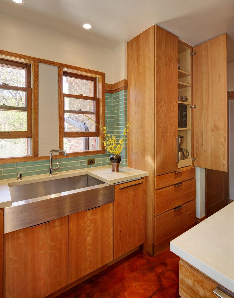 Photo of a mid-sized midcentury l-shaped eat-in kitchen in Milwaukee with a farmhouse sink, flat-panel cabinets, medium wood cabinets, green splashback, ceramic splashback, stainless steel appliances and with island.