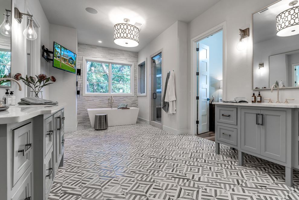 This is an example of a transitional bathroom in Austin with grey cabinets, a freestanding tub, grey walls, an undermount sink, multi-coloured floor, white benchtops and beaded inset cabinets.