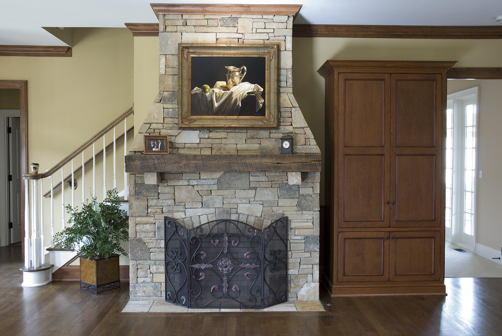 Inspiration for a mid-sized traditional formal open concept living room in Huntington with beige walls, dark hardwood floors, a standard fireplace, a stone fireplace surround, a concealed tv and brown floor.
