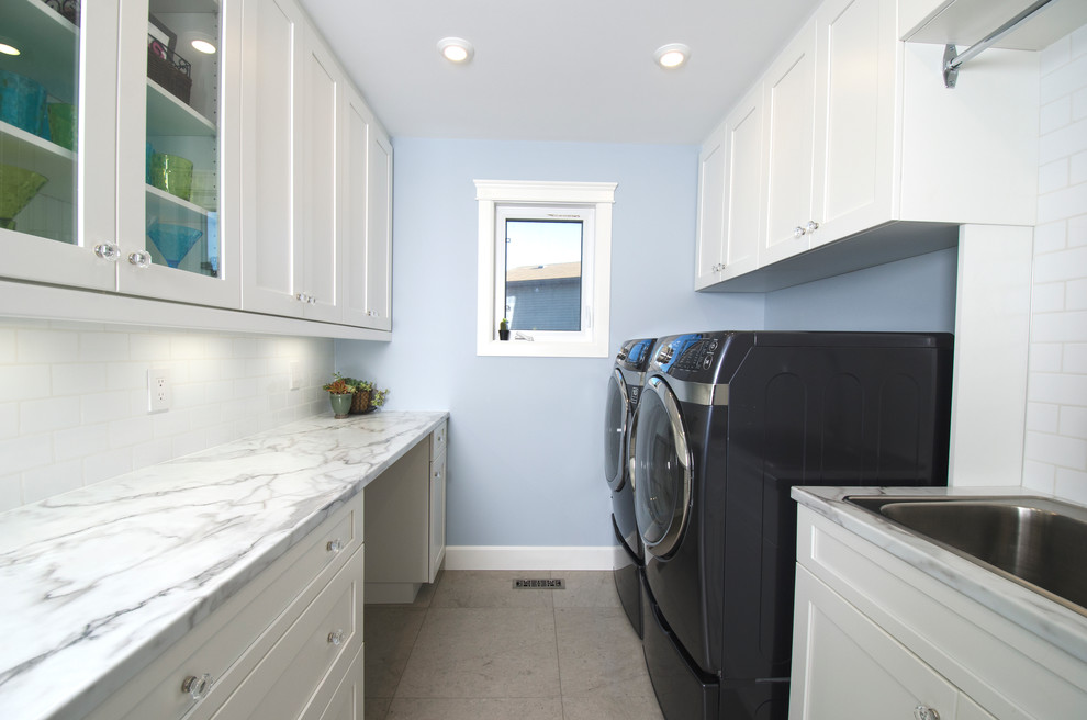 Design ideas for a transitional galley dedicated laundry room in Other with a single-bowl sink, flat-panel cabinets, white cabinets, laminate benchtops, blue walls, limestone floors and a side-by-side washer and dryer.