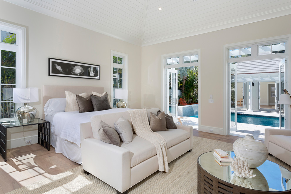 Large beach style bedroom in Miami with beige walls, light hardwood floors, no fireplace and beige floor.