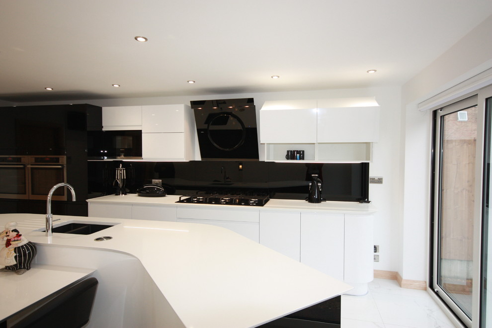 Inspiration for an expansive contemporary eat-in kitchen in Kent with a drop-in sink, flat-panel cabinets, white cabinets, quartzite benchtops, black splashback, glass sheet splashback, panelled appliances, porcelain floors, with island and white floor.
