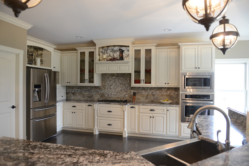 Inspiration for a huge transitional l-shaped medium tone wood floor eat-in kitchen remodel in Chicago with a farmhouse sink, raised-panel cabinets, white cabinets, granite countertops, beige backsplash, stone tile backsplash, stainless steel appliances and an island