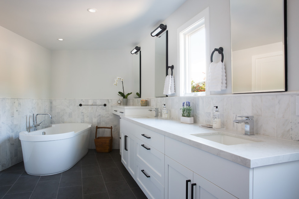 Photo of a large traditional master bathroom in San Francisco with shaker cabinets, white cabinets, a freestanding tub, gray tile, marble, white walls, slate floors, an undermount sink, marble benchtops, black floor and white benchtops.
