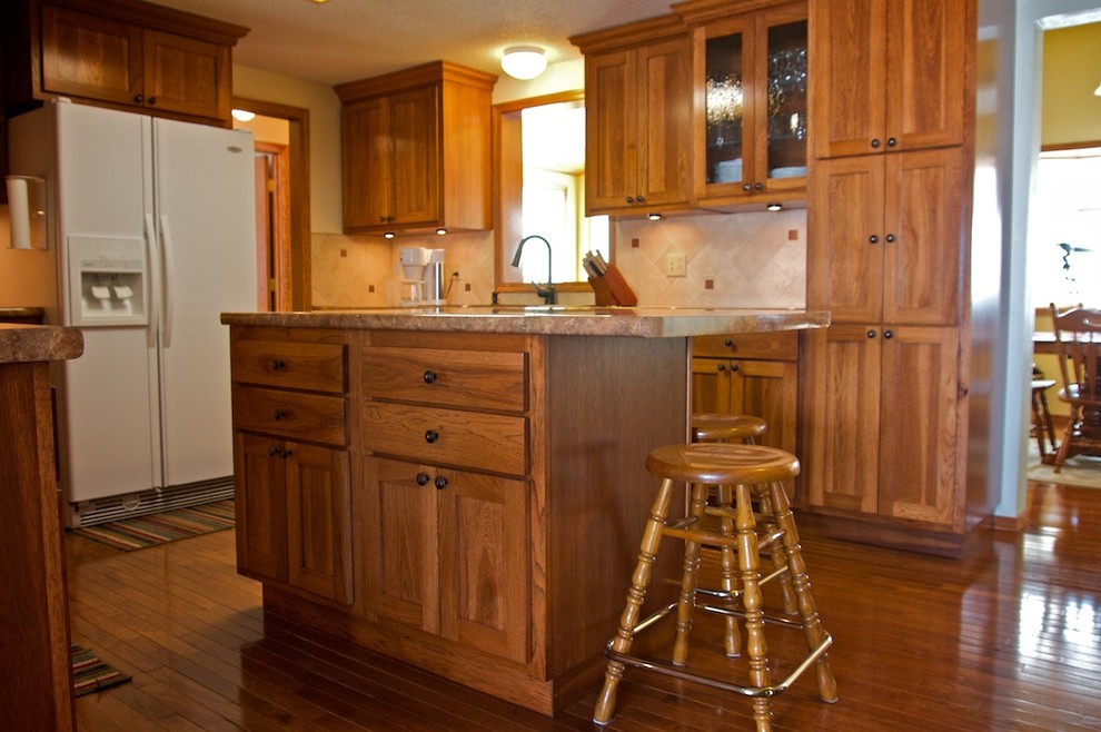 Example of a mid-sized u-shaped eat-in kitchen design with raised-panel cabinets, medium tone wood cabinets, laminate countertops, beige backsplash, stone tile backsplash, white appliances and an island
