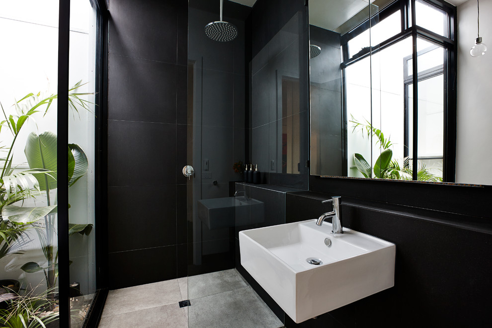 Contemporary bathroom in Melbourne with a wall-mount sink, an open shower, black tile, ceramic tile, black walls, ceramic floors and an open shower.