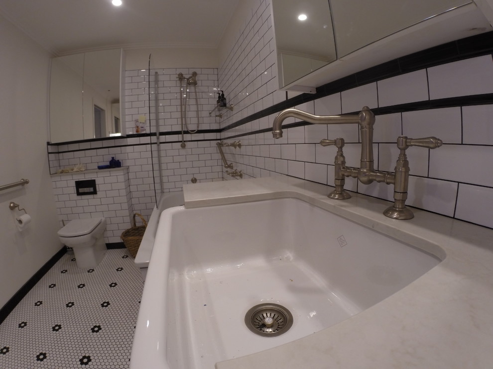 Photo of a mid-sized kids bathroom in Melbourne with a trough sink, shaker cabinets, grey cabinets, engineered quartz benchtops, a drop-in tub, a shower/bathtub combo, a one-piece toilet, white tile, ceramic tile, white walls and mosaic tile floors.