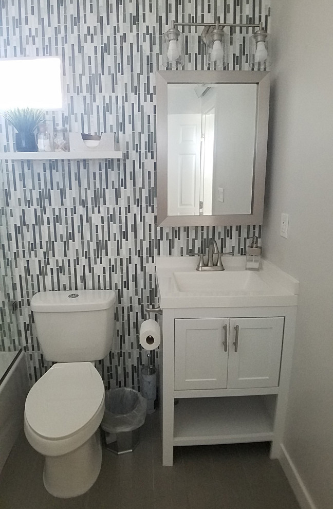 Design ideas for a mid-sized modern kids bathroom in Los Angeles with recessed-panel cabinets, white cabinets, a freestanding tub, a shower/bathtub combo, a two-piece toilet, gray tile, mosaic tile, beige walls, porcelain floors, an integrated sink, marble benchtops, grey floor, a sliding shower screen, white benchtops, a single vanity and a freestanding vanity.