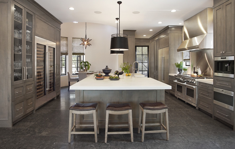 Inspiration for a large transitional u-shaped eat-in kitchen in Phoenix with a farmhouse sink, shaker cabinets, brown cabinets, metallic splashback, stainless steel appliances, with island, grey floor, white benchtop, marble benchtops, marble splashback and limestone floors.