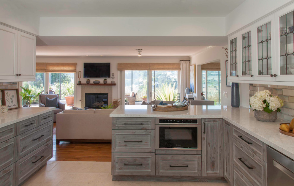 Inspiration for a mid-sized transitional u-shaped eat-in kitchen in San Diego with an undermount sink, shaker cabinets, distressed cabinets, quartz benchtops, blue splashback, ceramic splashback, stainless steel appliances, porcelain floors, a peninsula, beige floor and turquoise benchtop.