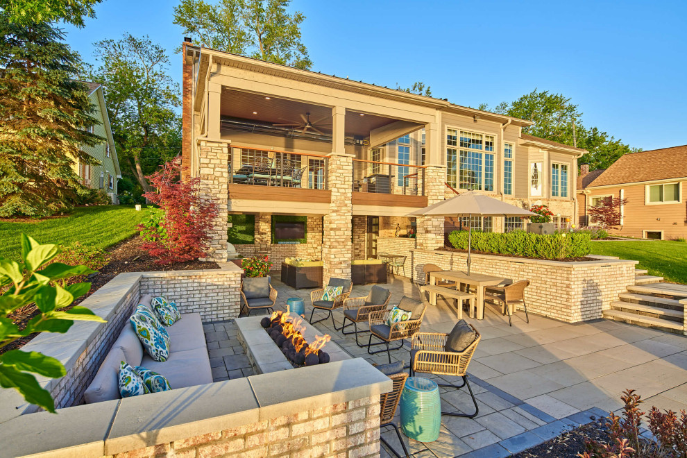 Cette image montre une grande terrasse arrière marine avec une cuisine d'été, des pavés en béton et une extension de toiture.