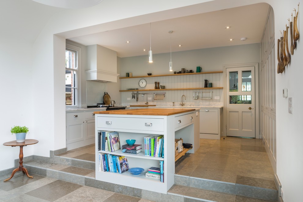 Large country u-shaped open plan kitchen in Oxfordshire with a farmhouse sink, shaker cabinets, grey cabinets, solid surface benchtops, white splashback, panelled appliances, ceramic floors and with island.