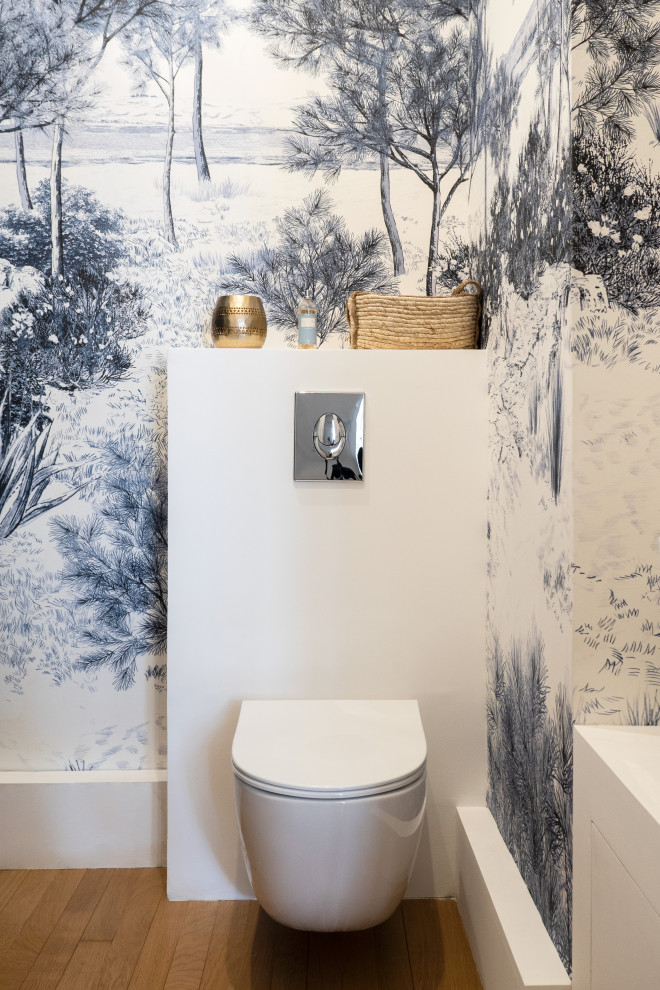 Ejemplo de aseo clásico pequeño con sanitario de pared, paredes azules, suelo de madera en tonos medios, suelo marrón y papel pintado