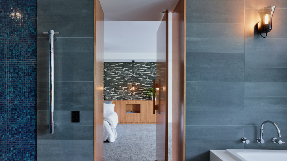 Photo of a mid-sized contemporary master wet room bathroom in Sydney with furniture-like cabinets, grey cabinets, a drop-in tub, a one-piece toilet, gray tile, porcelain tile, grey walls, porcelain floors, a vessel sink, solid surface benchtops, grey floor, a sliding shower screen and grey benchtops.