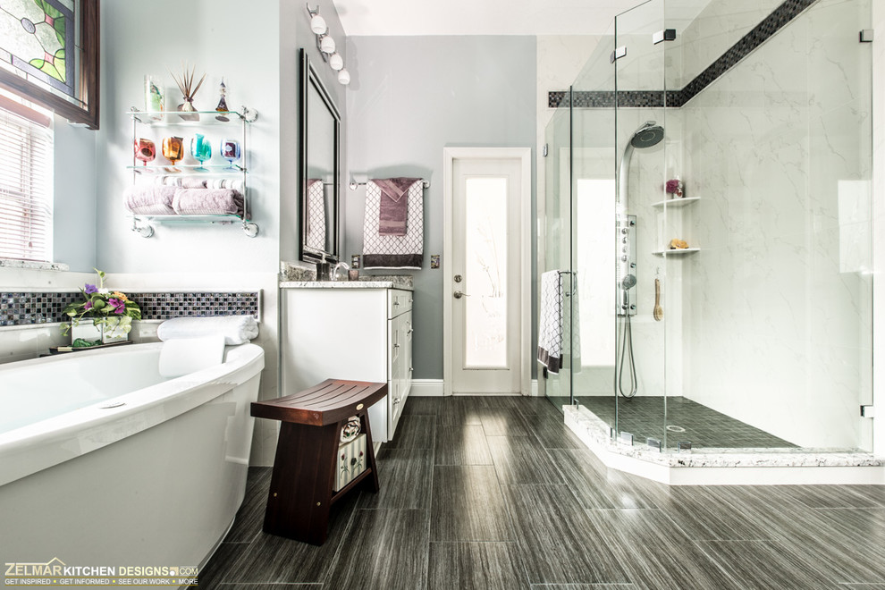 Photo of a mid-sized contemporary master bathroom in Orlando with an undermount sink, shaker cabinets, white cabinets, granite benchtops, a freestanding tub, gray tile, porcelain tile and porcelain floors.