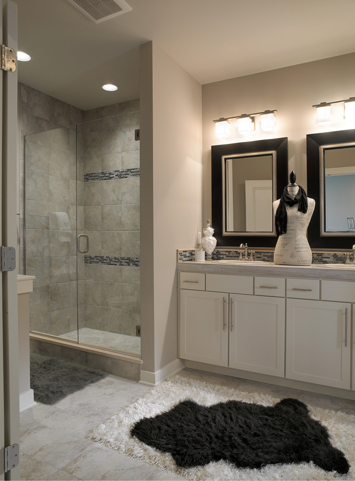 Corner shower - mid-sized transitional master gray tile and ceramic tile ceramic tile corner shower idea with shaker cabinets, white cabinets, laminate countertops, gray walls, a drop-in sink and a one-piece toilet