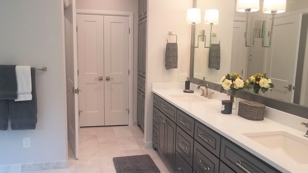 Photo of an expansive transitional master bathroom in Houston with furniture-like cabinets, grey cabinets, an undermount tub, a curbless shower, a one-piece toilet, marble, grey walls, marble floors, an undermount sink, engineered quartz benchtops, white floor, a hinged shower door and white benchtops.