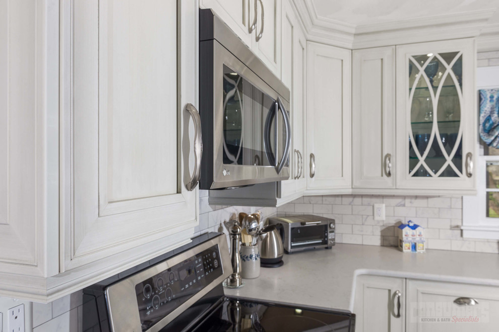 Eat-in kitchen - mid-sized u-shaped porcelain tile eat-in kitchen idea in New York with an undermount sink, recessed-panel cabinets, white cabinets, quartz countertops, white backsplash, ceramic backsplash, stainless steel appliances and no island