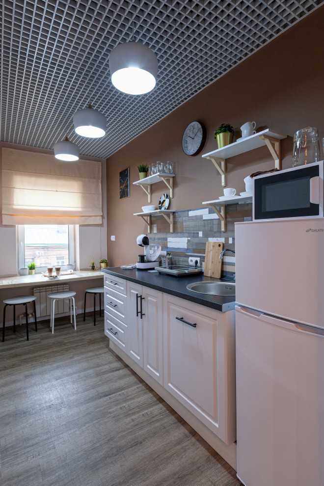 Стильный дизайн: маленькая прямая кухня в скандинавском стиле с обеденным столом, фасадами с утопленной филенкой, белыми фасадами и столешницей из ламината без острова для на участке и в саду - последний тренд