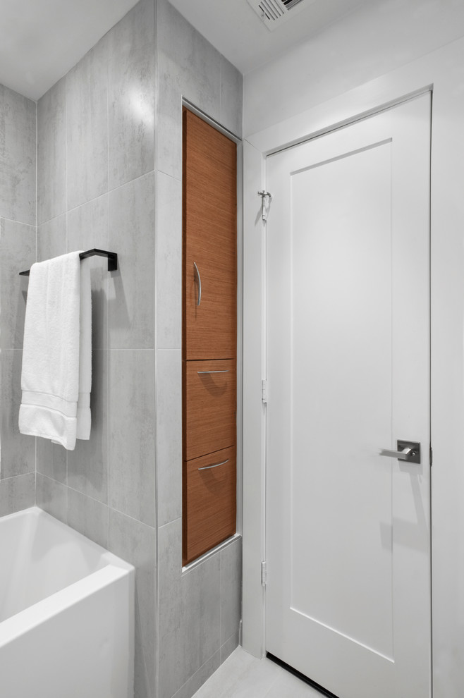This is an example of a mid-sized midcentury 3/4 bathroom in Houston with flat-panel cabinets, medium wood cabinets, an alcove tub, a shower/bathtub combo, gray tile, porcelain tile, grey walls, porcelain floors, an integrated sink, glass benchtops, grey floor and an open shower.
